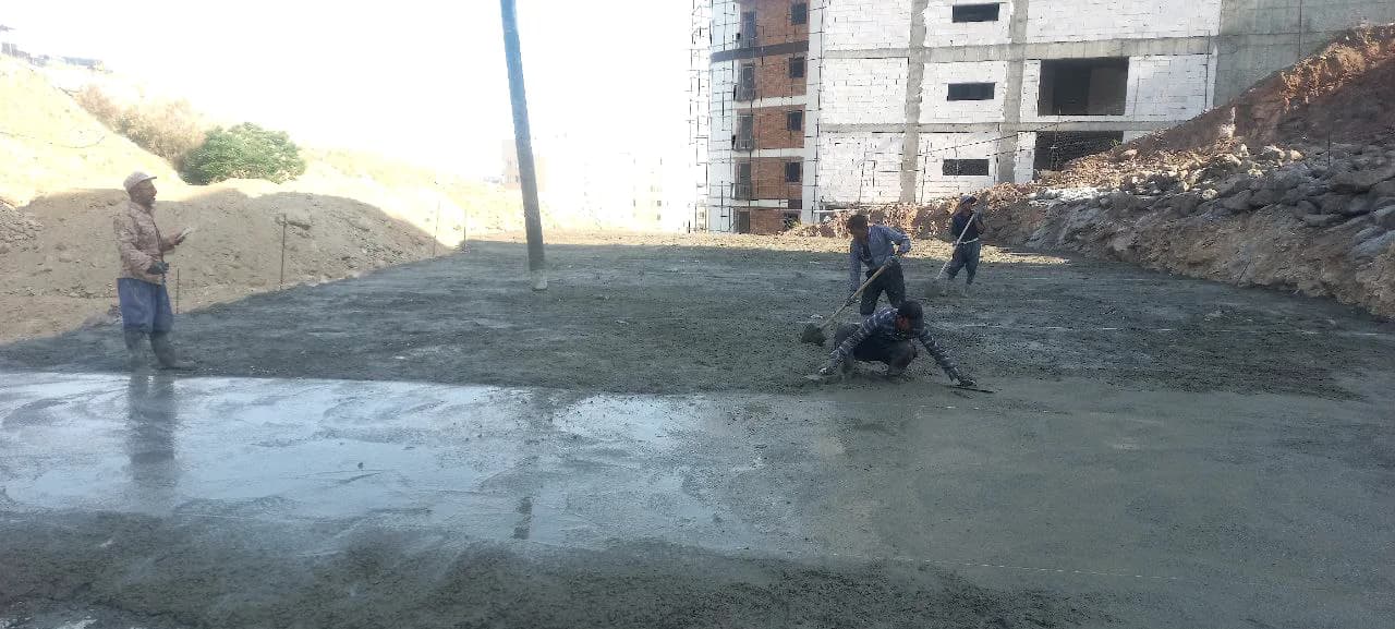 Workers placing and leveling concrete during early Aras construction works